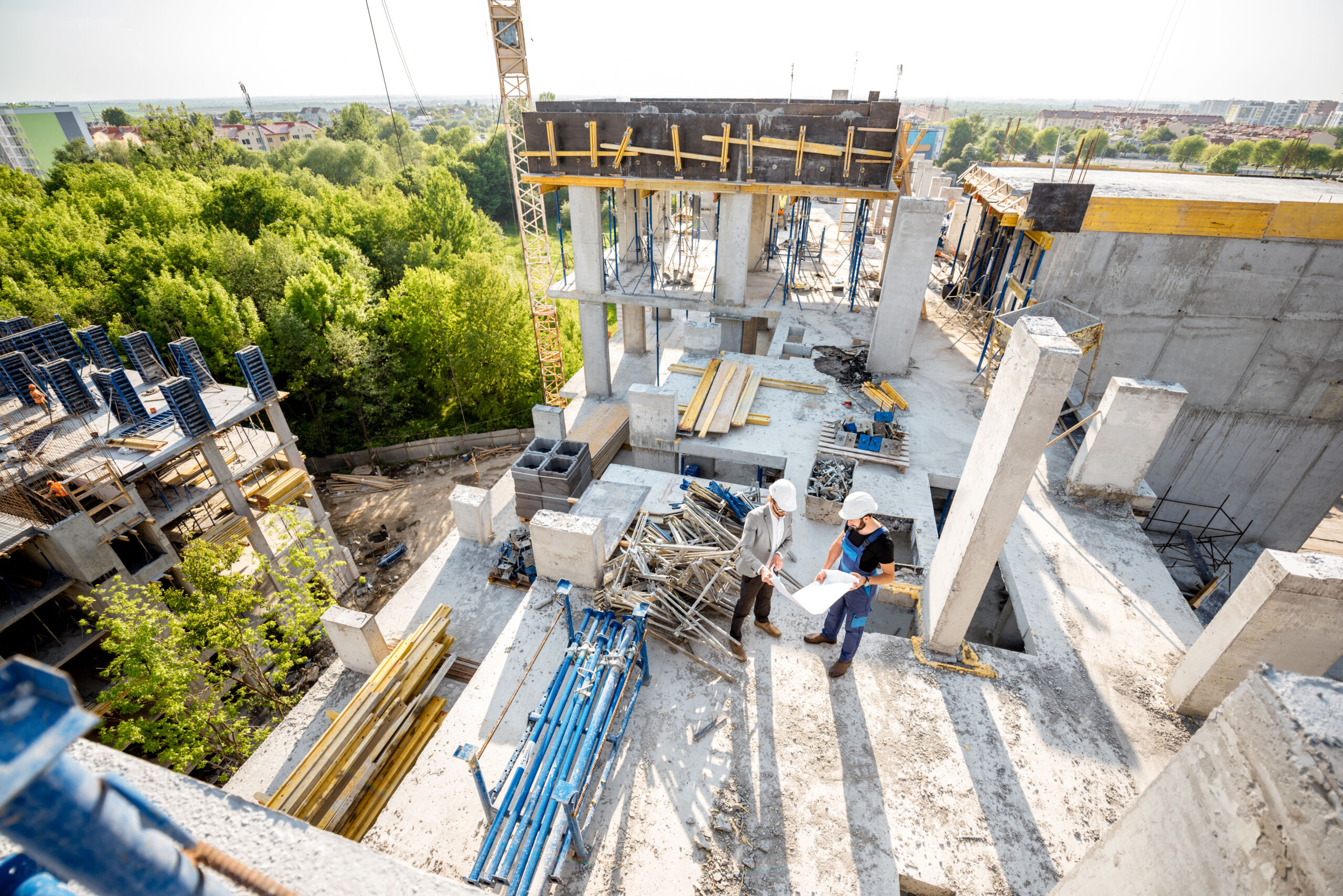 Top view on the construction site of residential buildings during the construction process with two workers standing with drawings